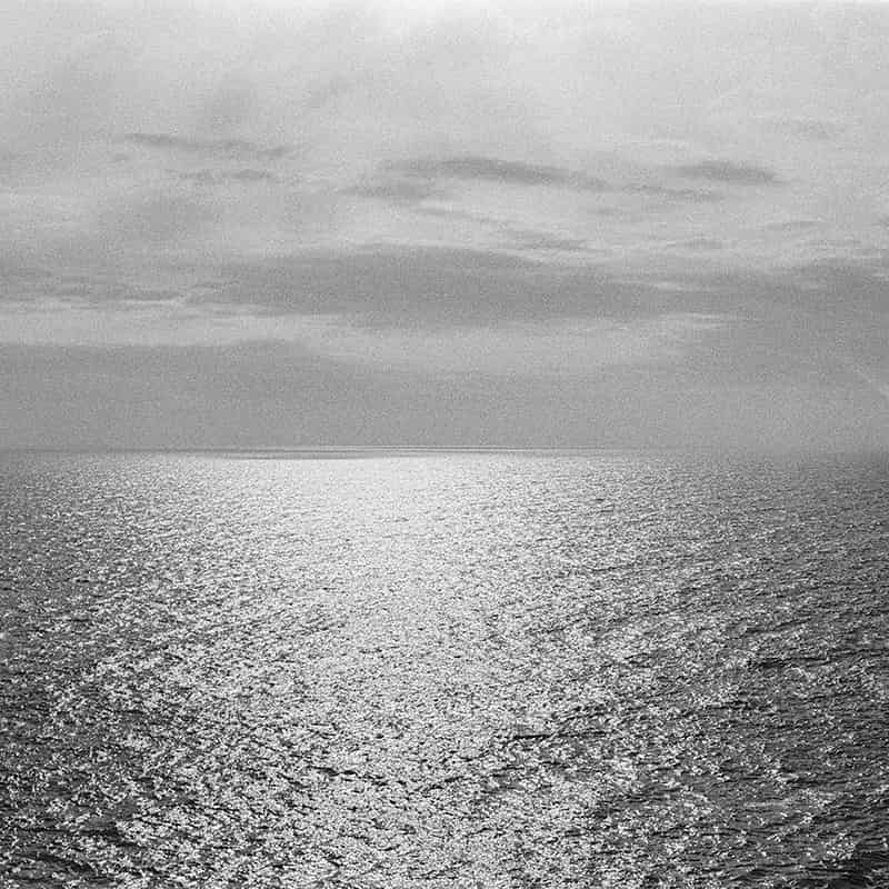 Meer und Himmel bestimmen je zur Hälfte die horizontal aufgebaute Schwarzweiss Fotografie. Leichte Wellen kräuseln die Wasseroberfläche und das diffuse Licht zaubert Silber auf sie. Der Uebergang vom Meer zum Himmel ist verschwommen. Der Himmel ist bewölkt und die Grautöne strukturieren ihn schön.