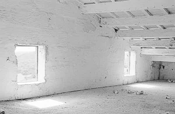 Immer wieder habe ich verlassene Fincas auf Menorca aufgesucht und in ihnen S/W-Fotos gemacht, so, wie ich die Räume auffand.  Im ersten Bild der Serie sieht man einen wenig beleuchteten Raum, zwei Waende definieren ihn. Die linke Wand nimmt ca. zwei drittel bis zur Zimmerecke ein. Das gesamte Foto erstrahlt in sanften Grautoenen. An der linken Wand ist ein Handwaschbecken befestigt. Es gibt keine Abflussrohre und keine Armatur. Ueber dem Waschbecken befindet sich ein Spiegel, der fast erblindet ist. Aus der Zimmerecke ragt eine Kloschuessel im Winkel von 45 Grad in den Raum. Sie ist mit einem Deckel verschlossen, aber auch hier gibt es weder Wasserzufluss noch Abfluss. Eine feine Patina aus Staub bedeckt alles.